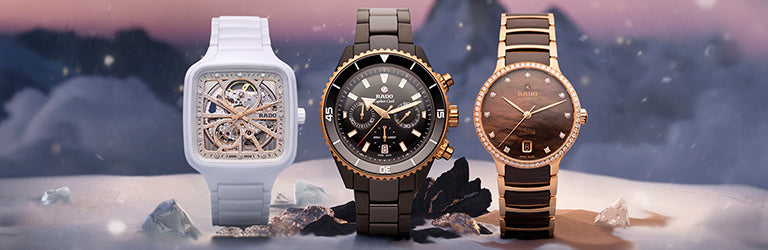 Three Rado watches displayed on a snowy holiday-themed background: a white skeleton dial watch on the left, a black ceramic chronograph watch in the center, and a rose gold and black ceramic watch with diamond accents on the right
